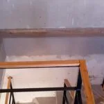 Detalle de baranda de hierro negro con pasamanos de madera en esquina de escalera, Temperley