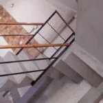 Escalera con baranda de hierro negro, pasamanos de madera y pared de tablillas de madera, Temperley